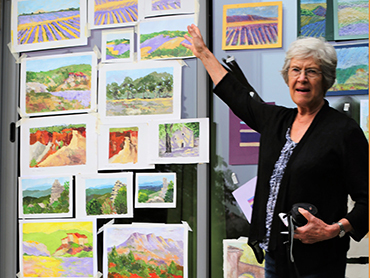 Woman artist in front of her paintings done during Walk the Arts art holidays in France