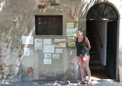 Artist showing her paintings on a wall during an art retreat in Italy by Walk the Arts