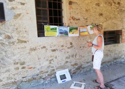 Woman showing her painting hang on a wall during an art workshop in Tuscany by Walk the Arts