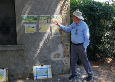 A painter showing his works during a plein air painting workshop in Italy by Walk the Arts