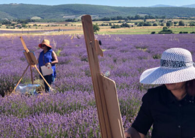 Two women in front of their easels painting on the lavender fields during an art retreat in Southern France offered by Walk the Arts