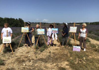 A group of painters in front of their paintings on a lavender fields during an plein air painting retreat in Southern France